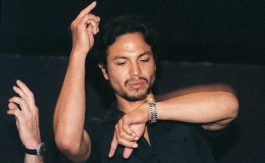 Benjamin Bratt looking at his watch with one hand raised